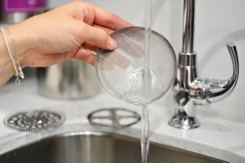 french-press-filter-mesh-being-washed-by-hand-in-a-sing-under-a-faucet-grosche-madrid