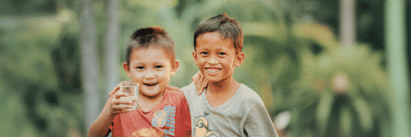 Two Safe Water Recipient Boys with a glass of clear and clean water, Gifts that give back, safe water project, clean water project, custom gifts, gift baskets, give back gifts